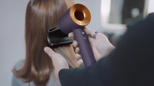 A stylist using the Dyson Supersonic Professional hair dryer in Bright copper.