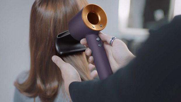 A stylist using the Dyson Supersonic Professional hair dryer in Bright copper.