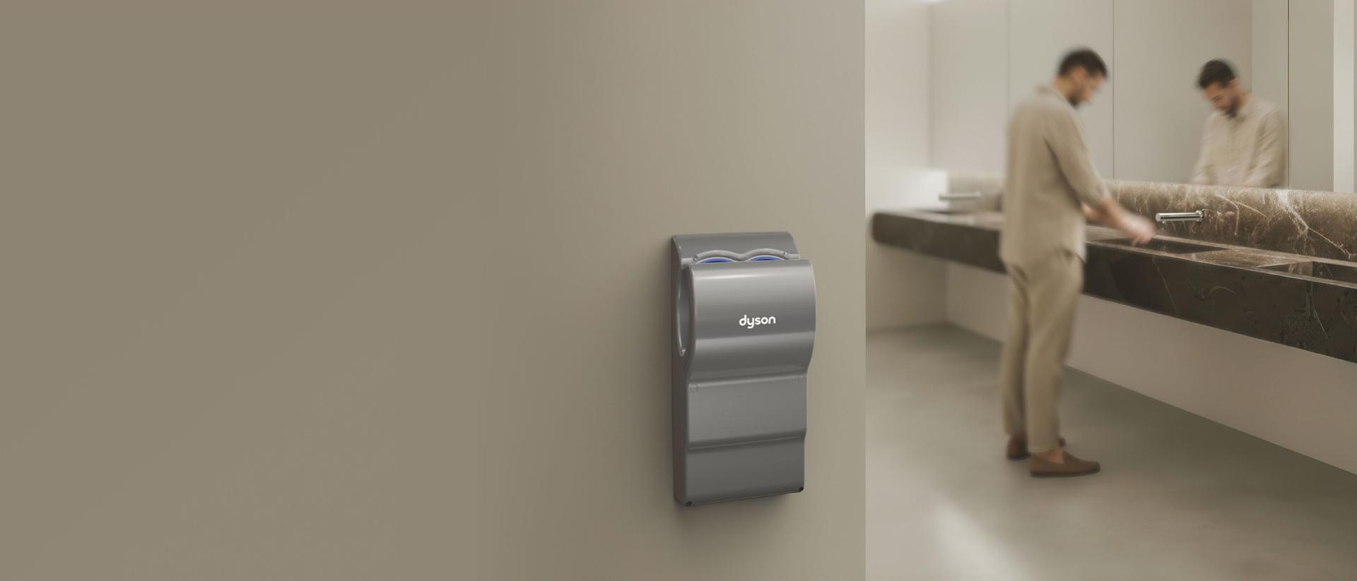 A Dyson Airblade dB hand dryer near a sink in a bathroom.