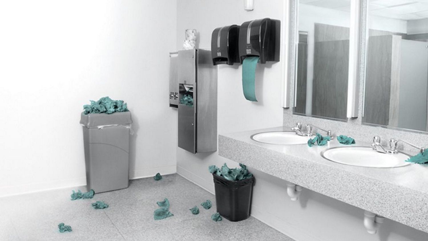 Single-use paper towels overflow onto the floor from a collection of bins in a bathroom.