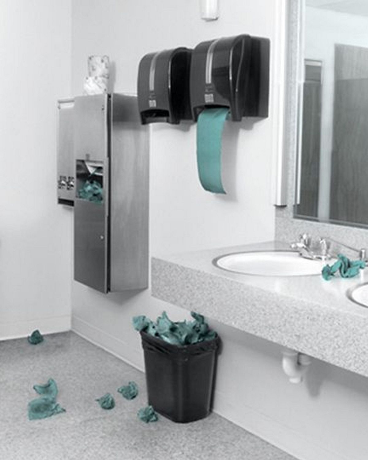 Single-use paper towels overflow onto the floor from a collection of bins in a bathroom.
