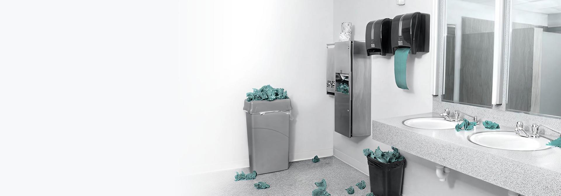Single-use paper towels overflow onto the floor from a collection of bins in a bathroom.