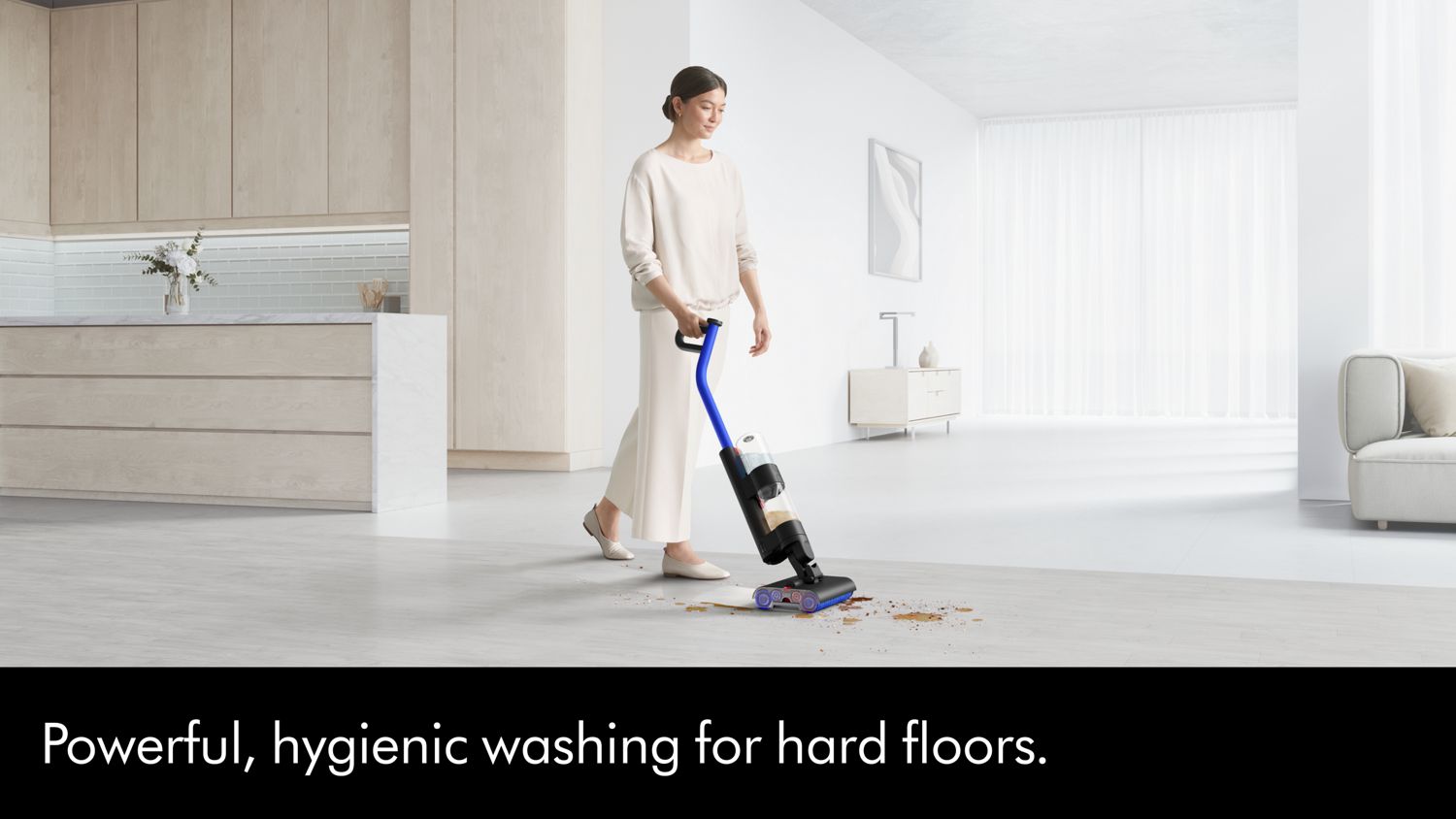 The Dyson WashG1 wet floor cleaner is used by a woman to clean a spill.