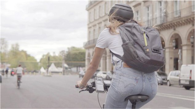 Eine Dame fährt Fahrrad mit einem von Dyson entwickeltem Luftqualitäts-Test-Rucksack