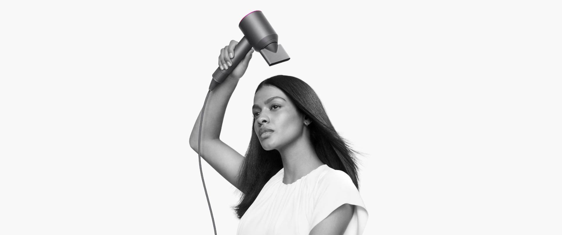 Kobieta susząca włosy suszarką do włosów Dyson Supersonic