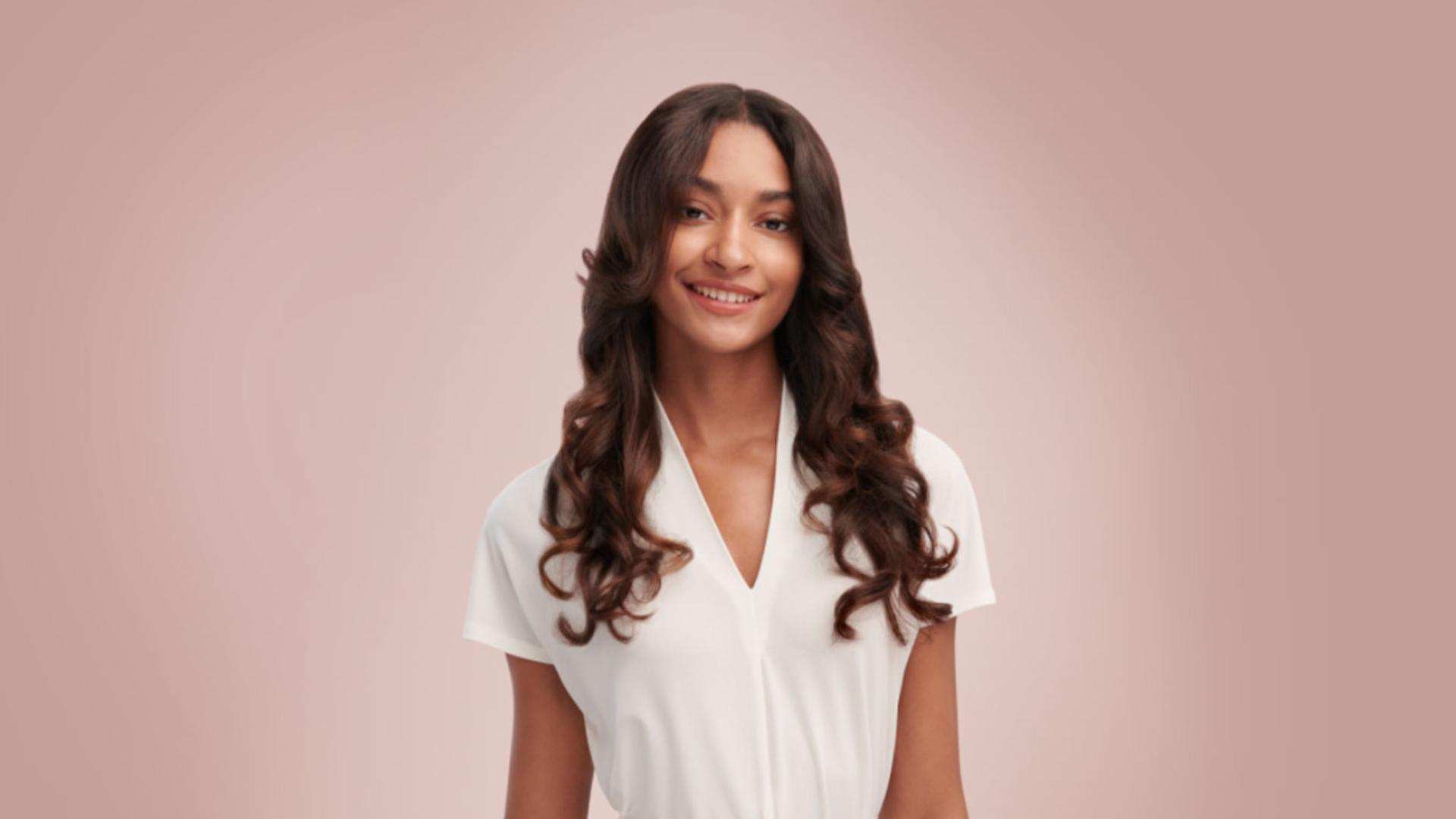 Modelka z falowanymi włosami, wystylizowanymi urządzeniem do stylizacji włosów Dyson