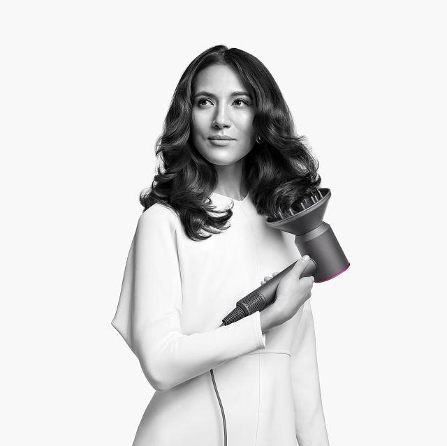 Woman with the Dyson Supersonic hair dryer with the diffuser attachment.
