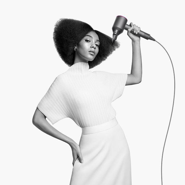 Woman with the Dyson Supersonic hair dryer with the diffuser attachment.