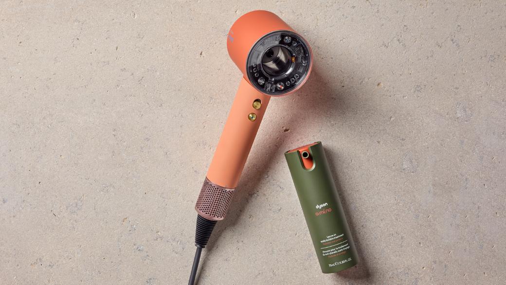 Dyson Supersonic Nural hair dryer on a rattan chair with Dyson Chitosan Pre-style cream.