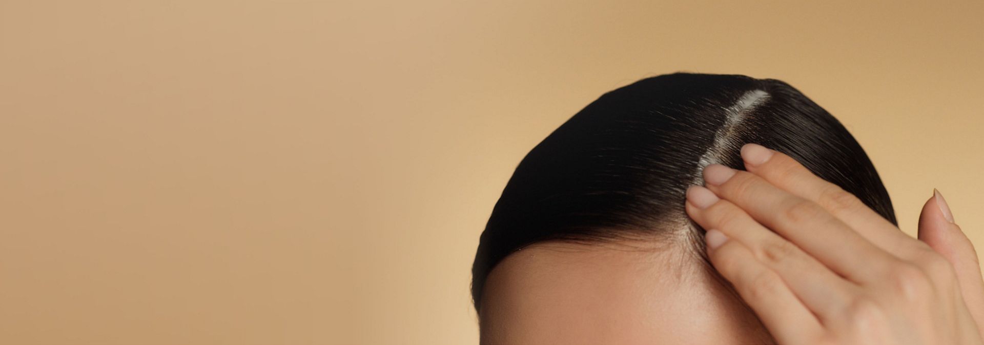 A model with coily hair styled into braids touches their scalp.