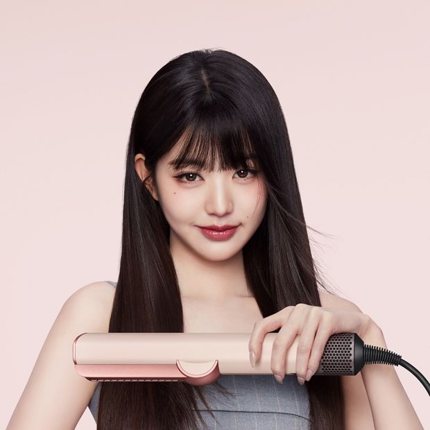 Model smooths and straightens her hair with the Dyson Airstrait dryer and straightener.