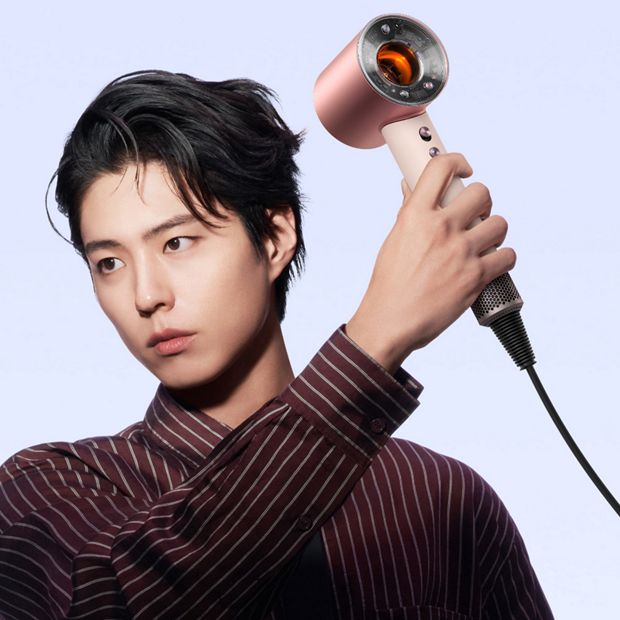 Model dries his hair with the Dyson Supersonic r hair dryer.