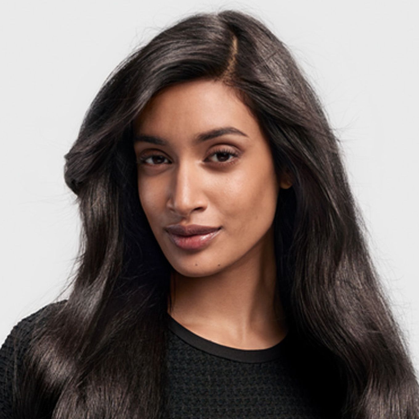 A dark-haired model with straight hair styled with the Dyson Airwrap i.d. multi-styler and dryer.