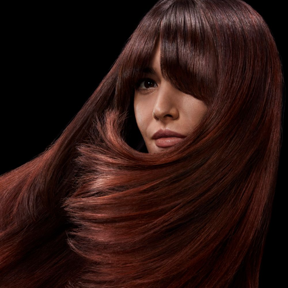 A brunette model with shiny hair styled with Dyson Chitosan products.