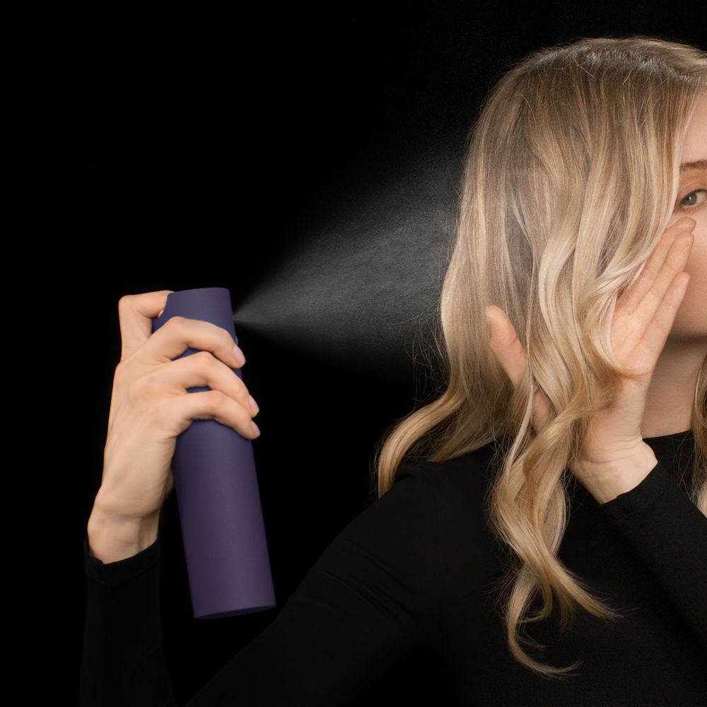 Dyson Chitosan Multi-use styling spray is sprayed onto blonde hair.