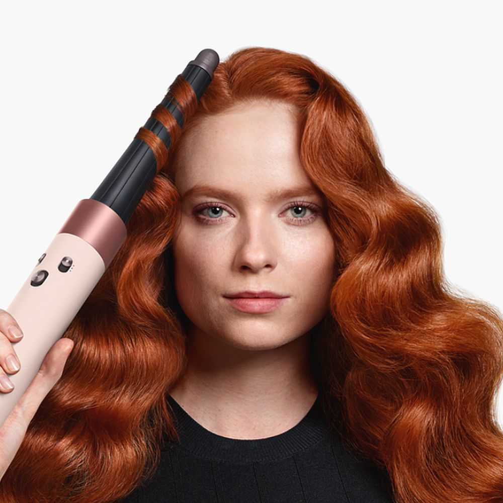 Model curling hair with the Dyson Airwrap ID multi-styler and dryer.