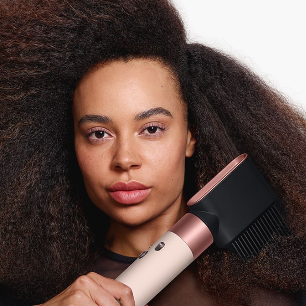 A model uses the Dyson Airwrap i.d. multi-styler and dryer to style her hair.