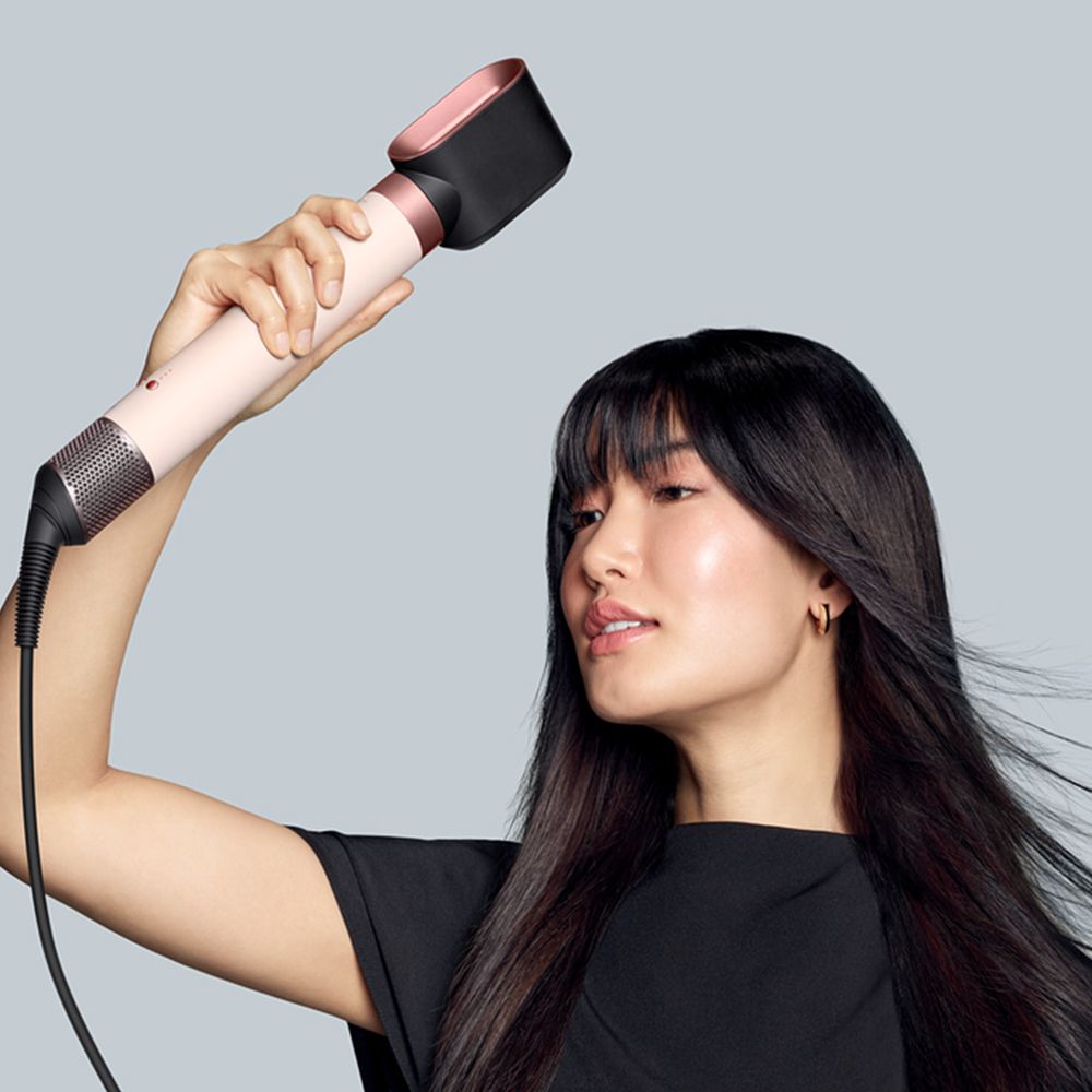 Dyson Airwrap Co-anda2x multi-styler and dryer used by a model to dry her hair.