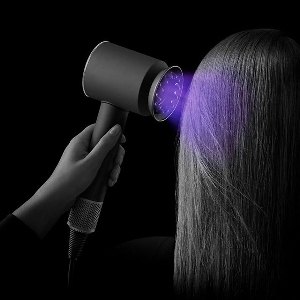 A model uses the Dyson Supersonic Nural hair dryer to dry her hair.