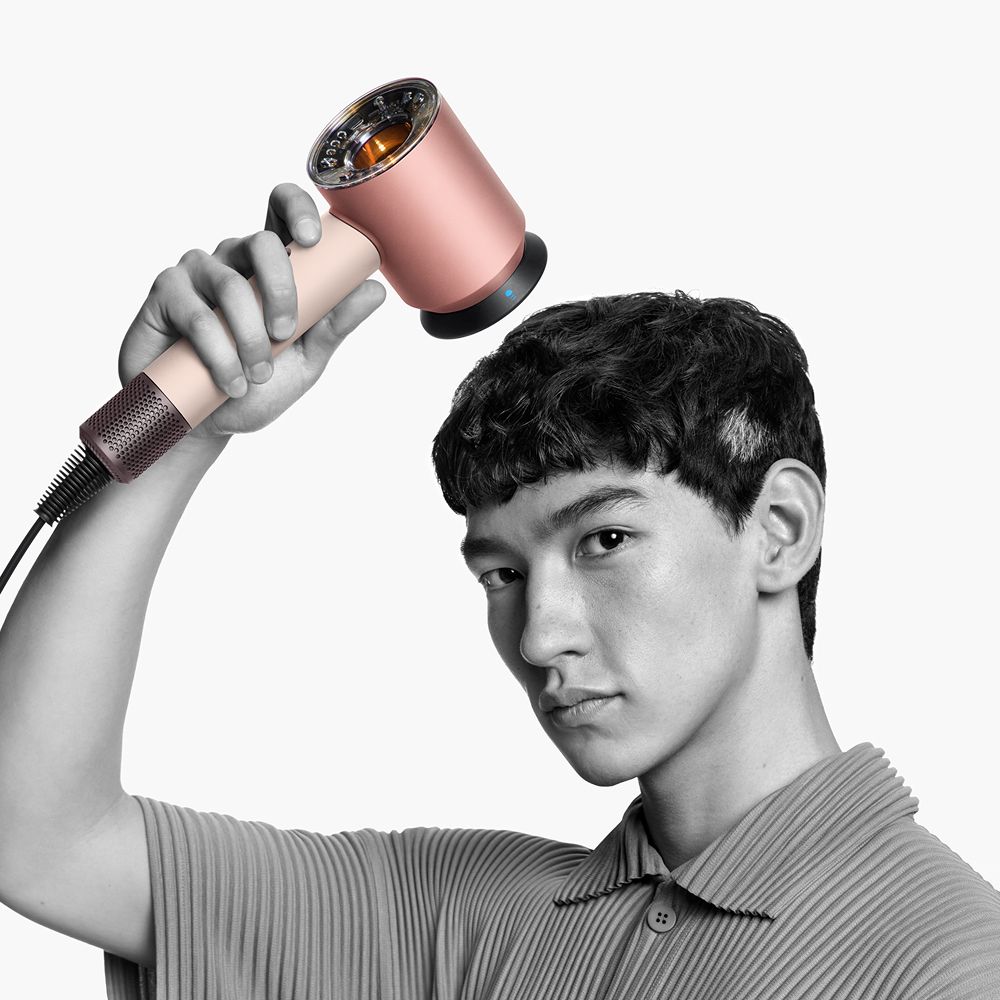  A model holds the Dyson Supersonic Nural hair dryer with the Styling concentrator attachment.