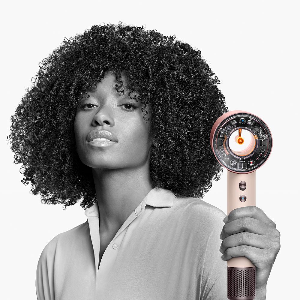 Model drži Dyson Supersonic Nural sušilo za kosu.