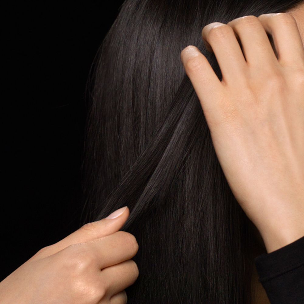 A dark-haired model styles her hair with Dyson products.