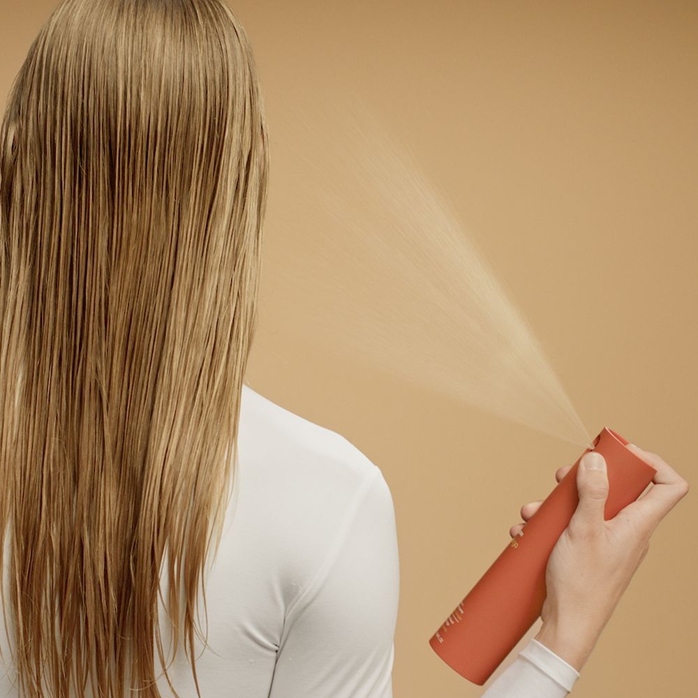 A blonde model shows off her smooth hair after using Dyson Omega products.