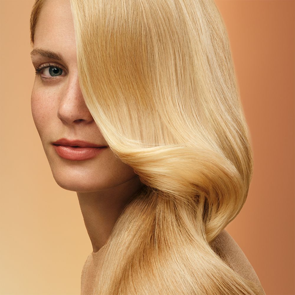 A curly haired model shows off her nourished hair after using Dyson Omega products.