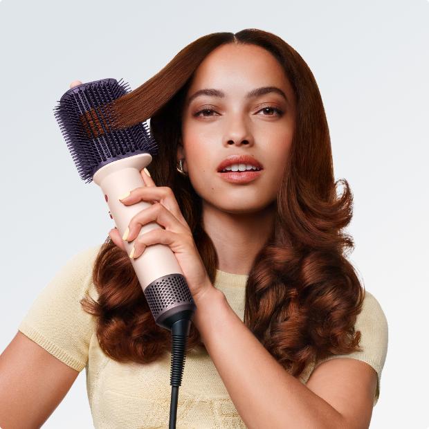 Model styles her hair with the Dyson Airsmooth styling brush.