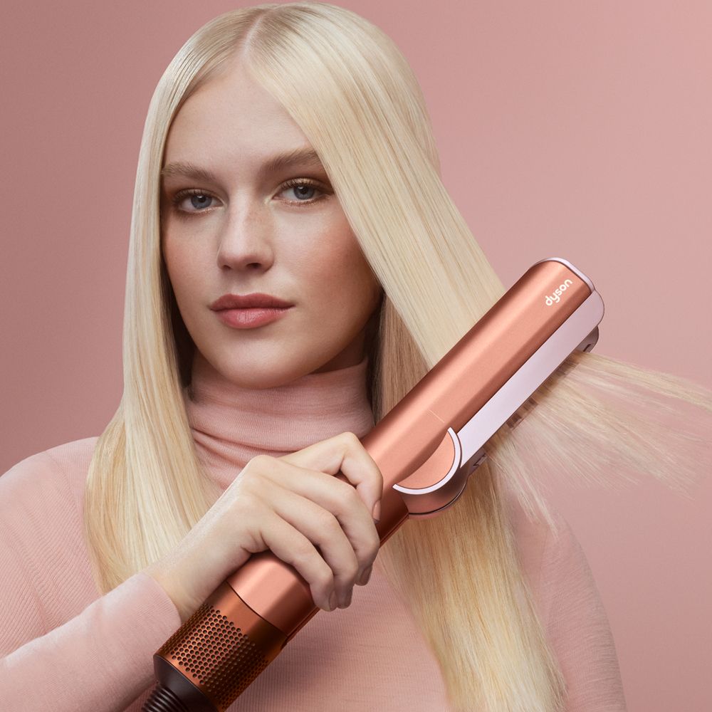 Model straightens her hair with the Dyson Airstrait dryer and straightener.