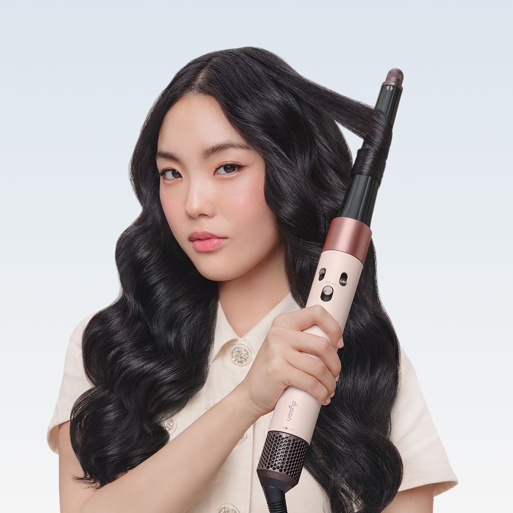 Model curls her hair with a Dyson Airwrap multi-styler and dryer.