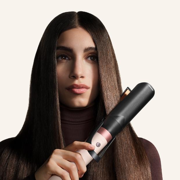 Dyson Airwrap Co-anda2x saç şekillendirme ve kurutma seti ile saçına bukle yapan bir model.