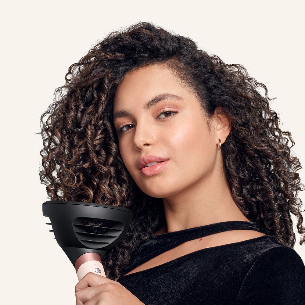 Model dries her hair with the Dyson Airwrap Co-anda2x multi-styler and dryer.