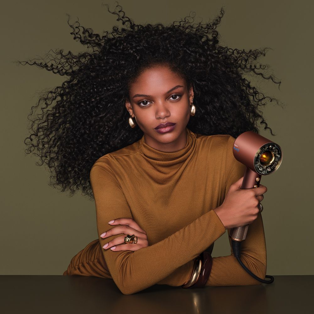 Model dries her hair with the Dyson Supersonic Nural hair dryer.