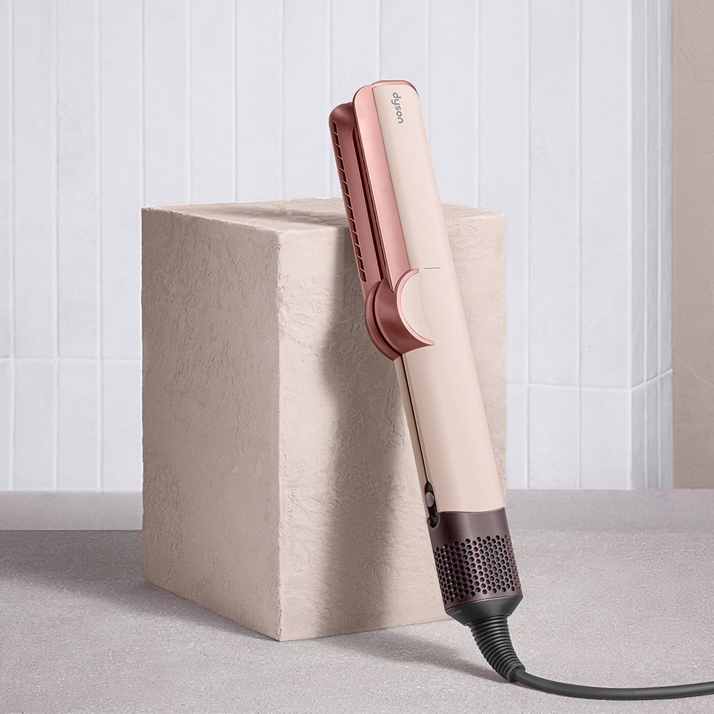 Model straightens her hair with the Dyson Airstrait dryer and straightener.