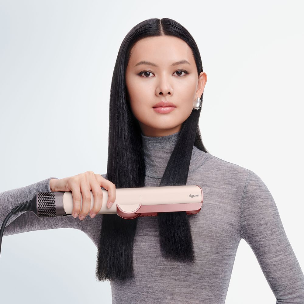 Model straightens her hair using the Dyson Airstrait dryer and straightener.