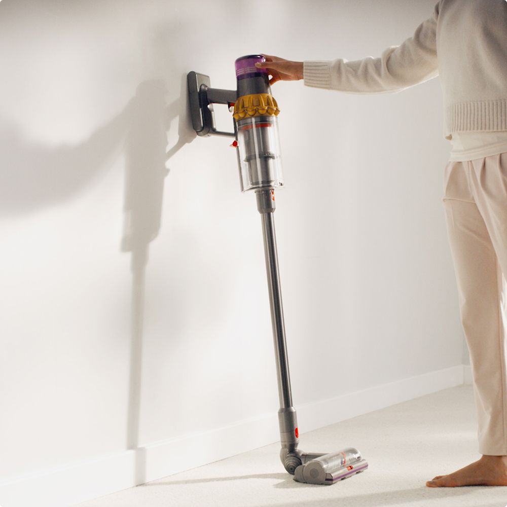 A Dyson vacuum is retrieved from its wall dock.