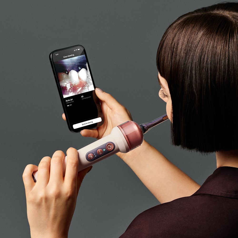 Person uses the MyDyson app to see a live view from their Dyson CameraJet toothbrush as they brush their teeth.