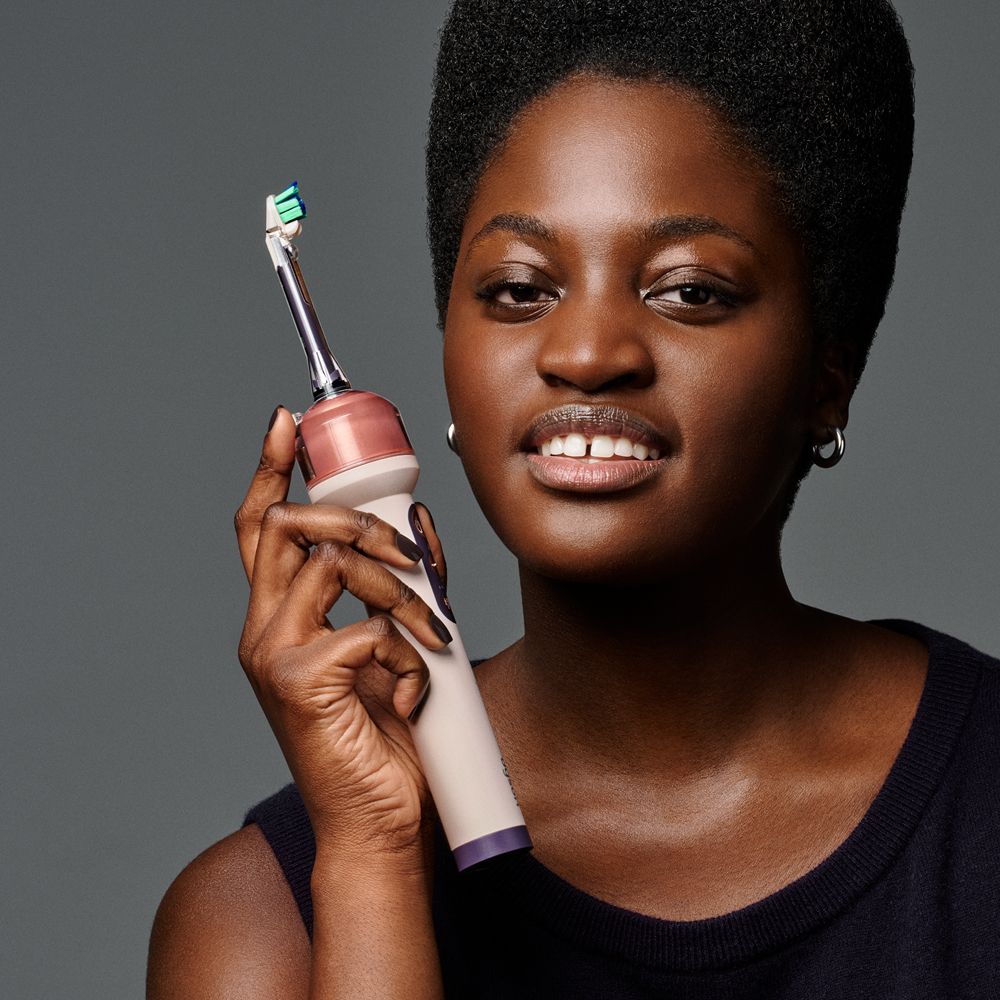 Model holds the Dyson CameraJet toothbrush.