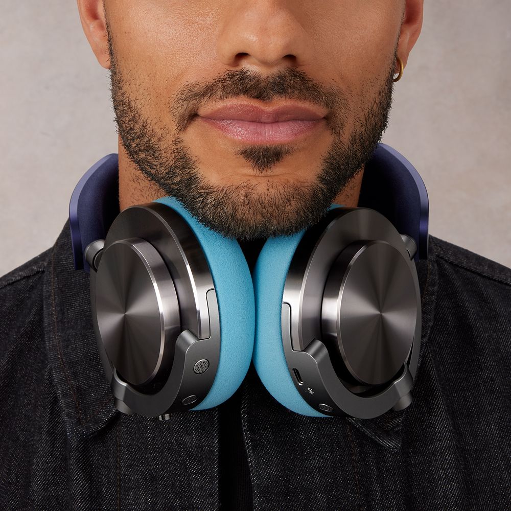 A person with ontrac headphones around their neck, the cushions are sky blue with the outer caps in CNC black nickel.