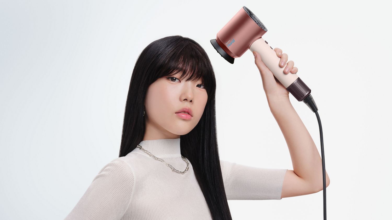 A model uses the Dyson Supersonic Nural hair dryer to style her hair.