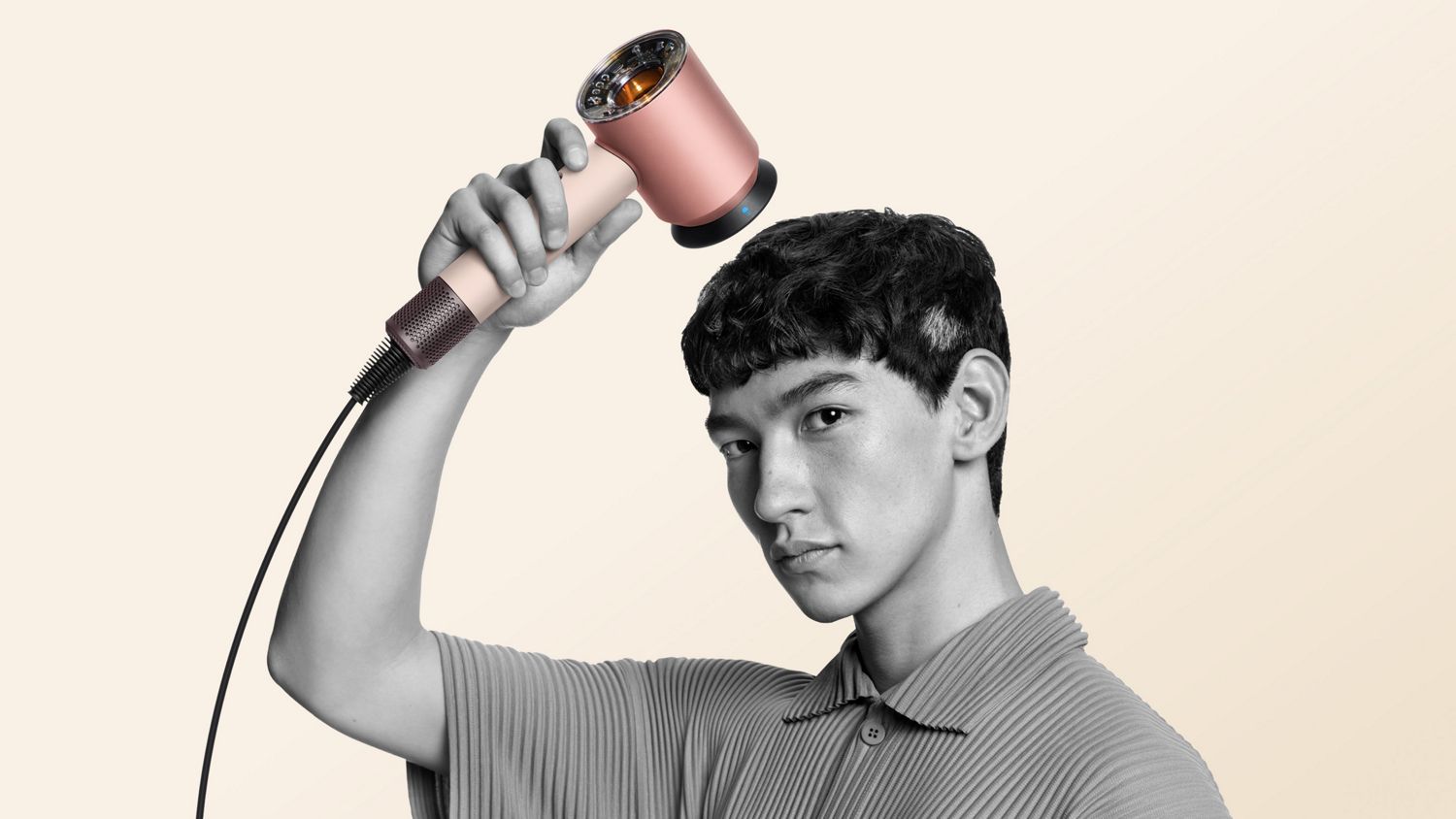 A model with a short textured crop uses the Smoothing nozzle to simultaneously style and dry his hair.