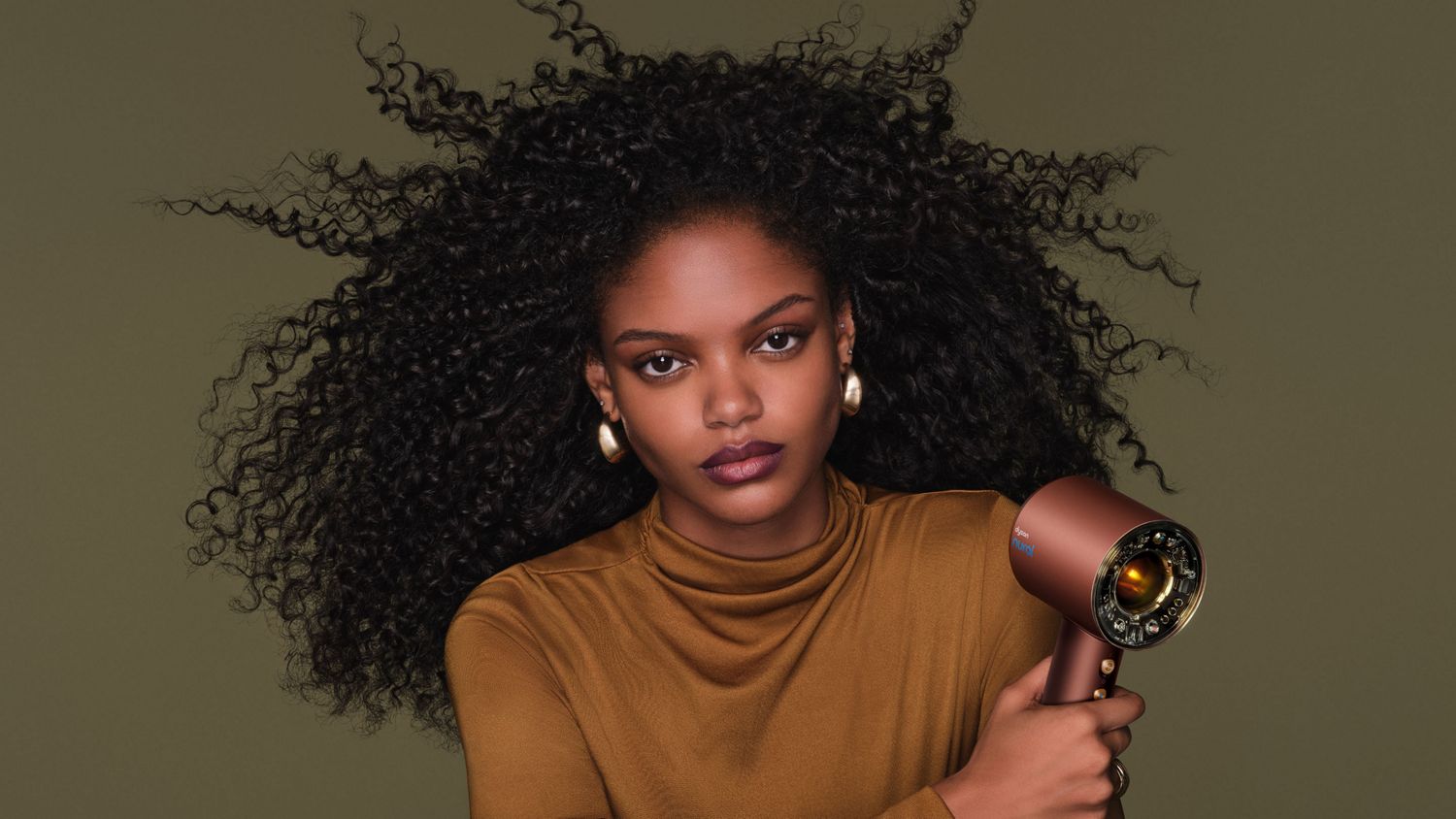 Model dries her hair with the Dyson Supersonic Nural hair dryer.