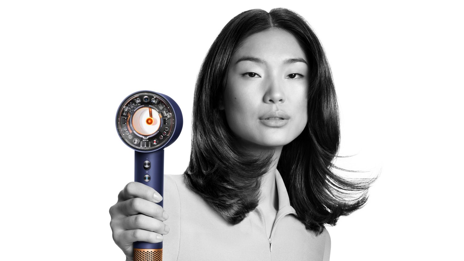 The Dyson Supersonic Nural hair dryer held by a model with straight, dark hair.