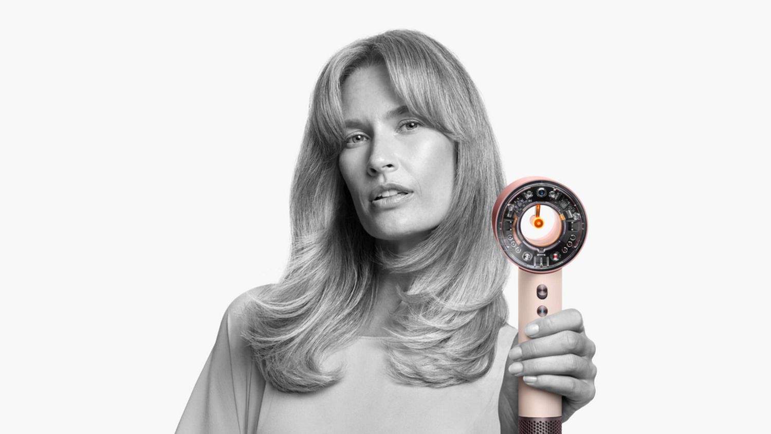 Model with styled hair holding the Dyson Supersonic Nural hair dryer.