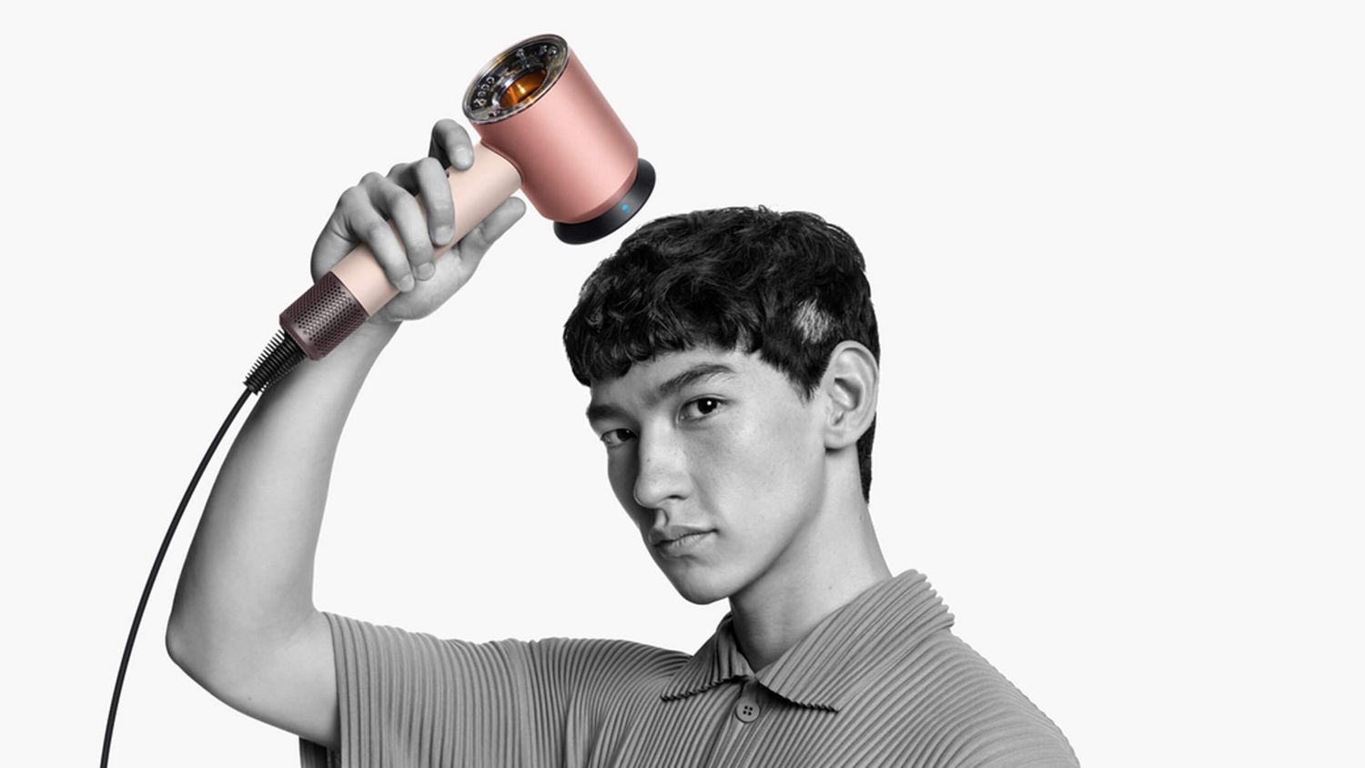 Male model holding the Supersonic Nural hair dryer with the Gentle air attachment near his head as he dries his hair.