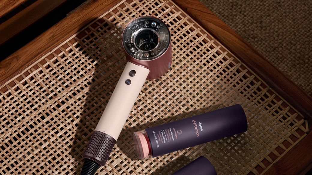 Dyson Supersonic Nural hair dryer on a rattan chair with Dyson Chitosan Pre-style cream. 