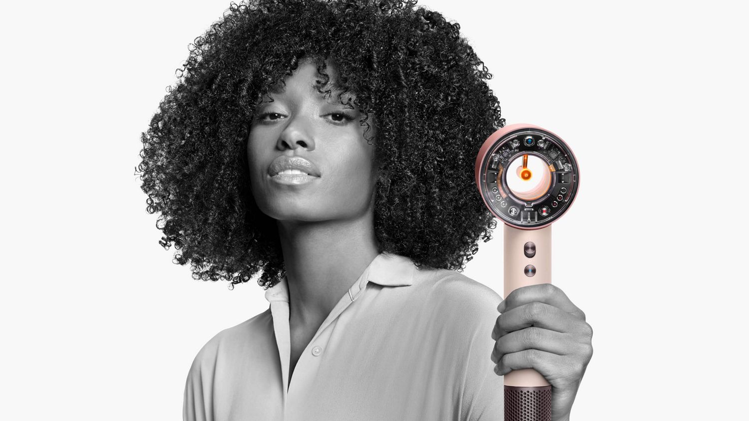 Model with styled hair holding the Dyson Supersonic Nural hair dryer.