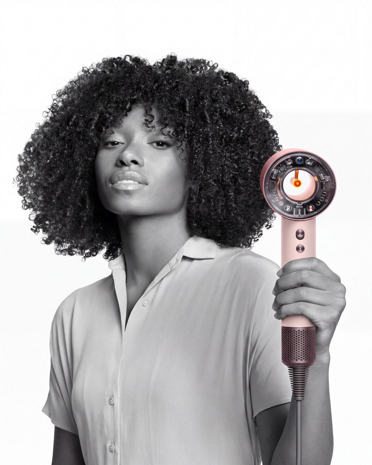 Modelo con cabello moldeado sosteniendo el secador de pelo Dyson Supersonic Nural.