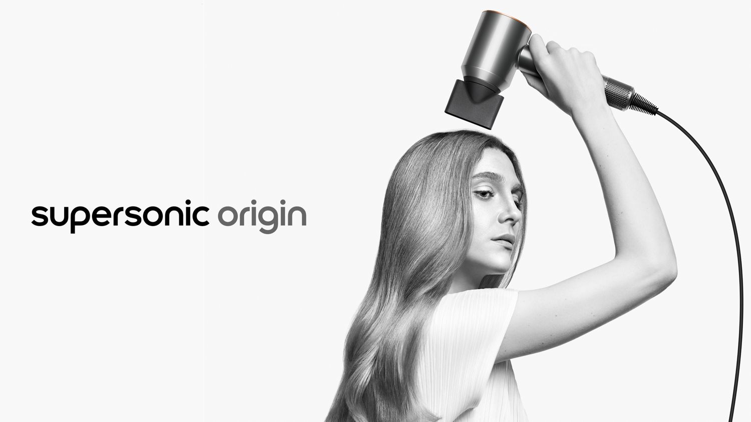 A model styles her long hair with the Dyson Supersonic Origin hair dryer and the Styling concentrator attachment.